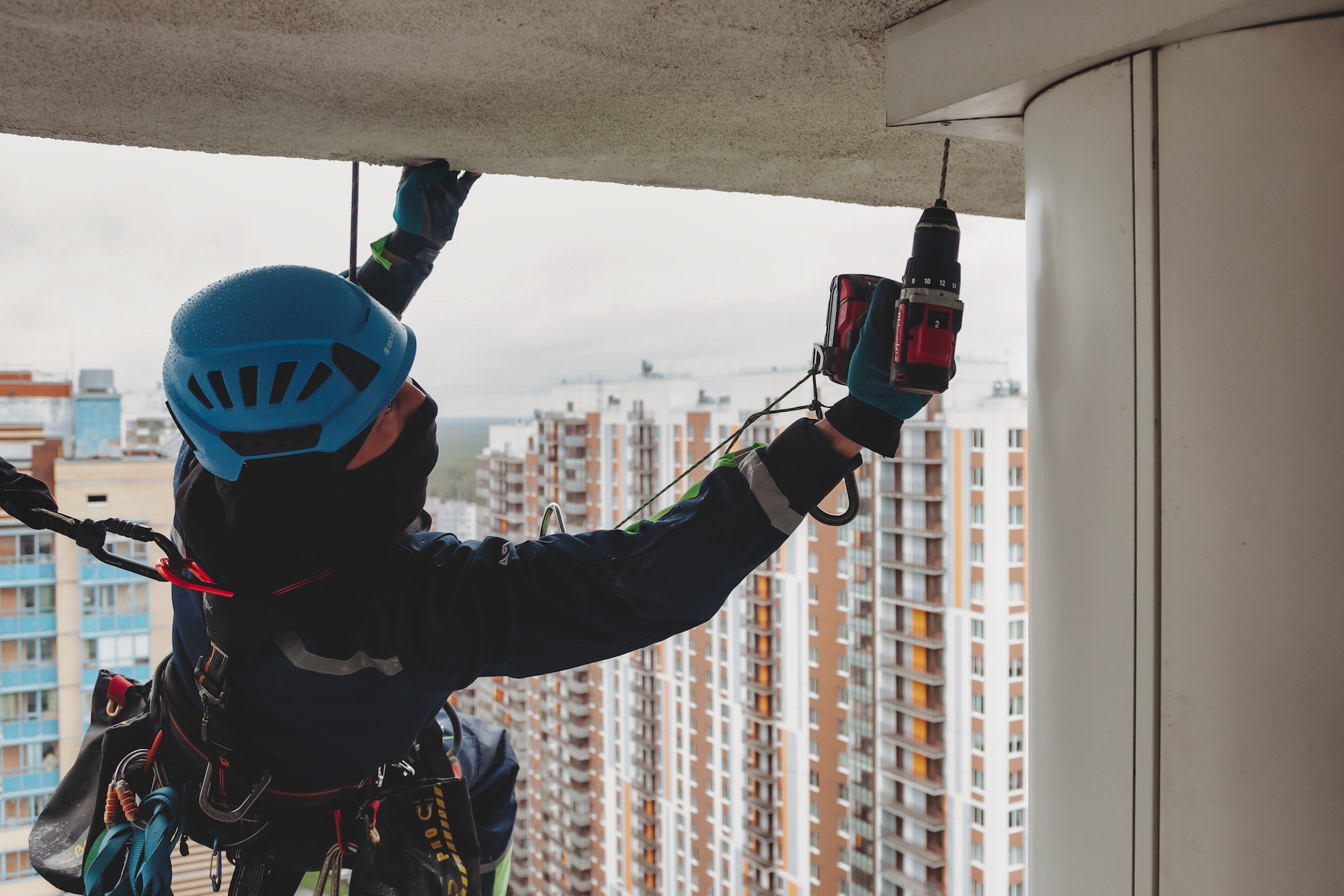An industrial climber performs installation work on a building in a megalopolis