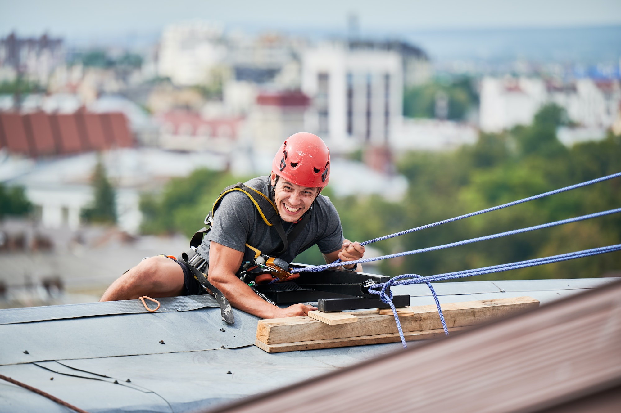 Industrial mountaineering worker cleaning window outside building.